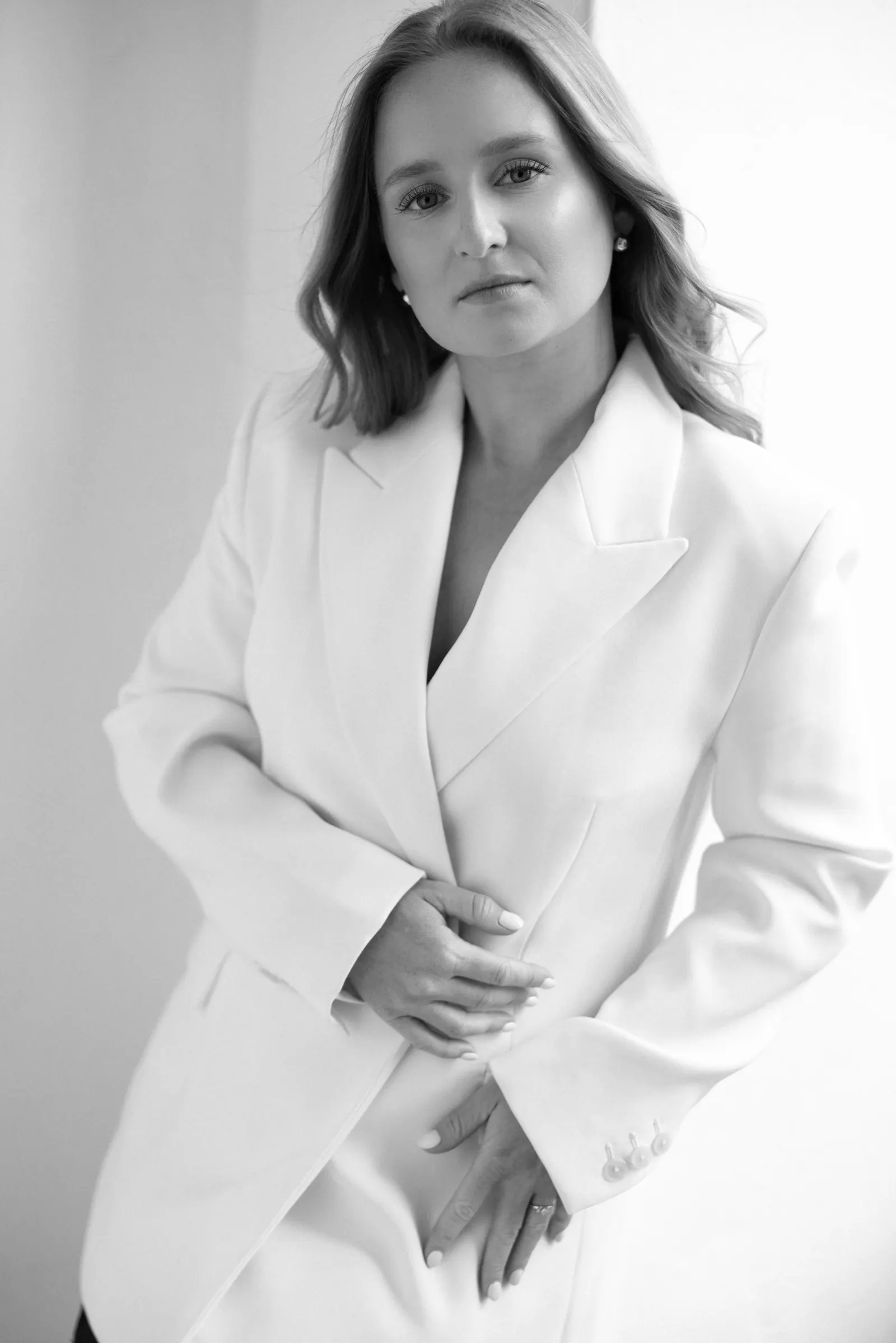 Black and white portrait of Aneta Studna, Prague wedding photographer, in a white blazer