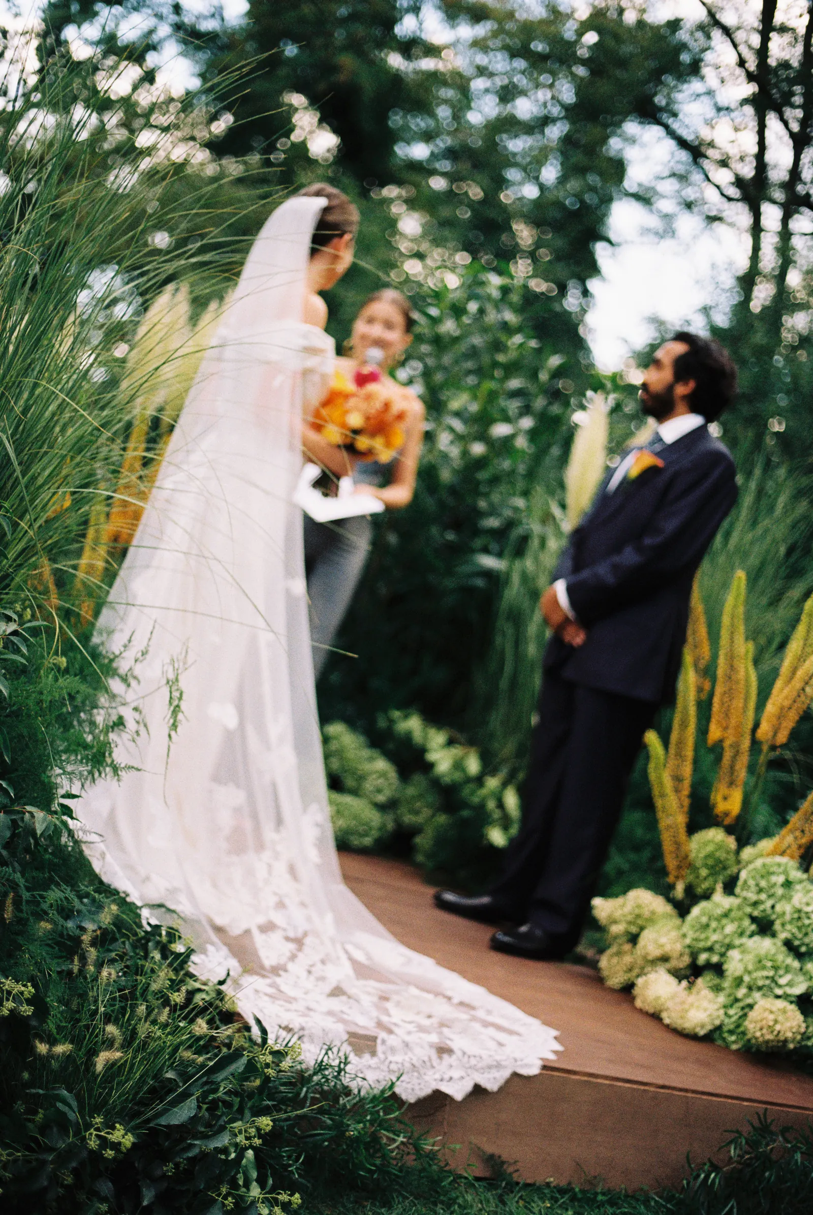 35mm film photo of a garden wedding ceremony with the bride’s long lace train