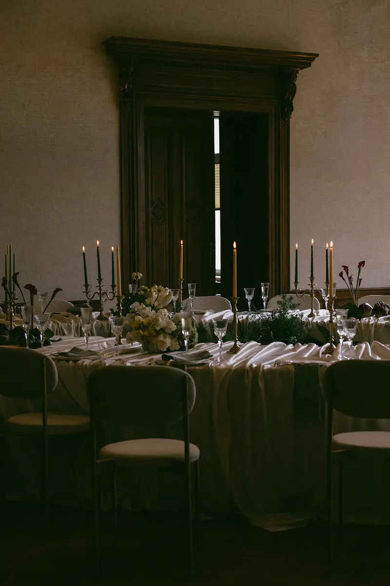Moody candlelit reception table in front of a tall dark wooden doorway