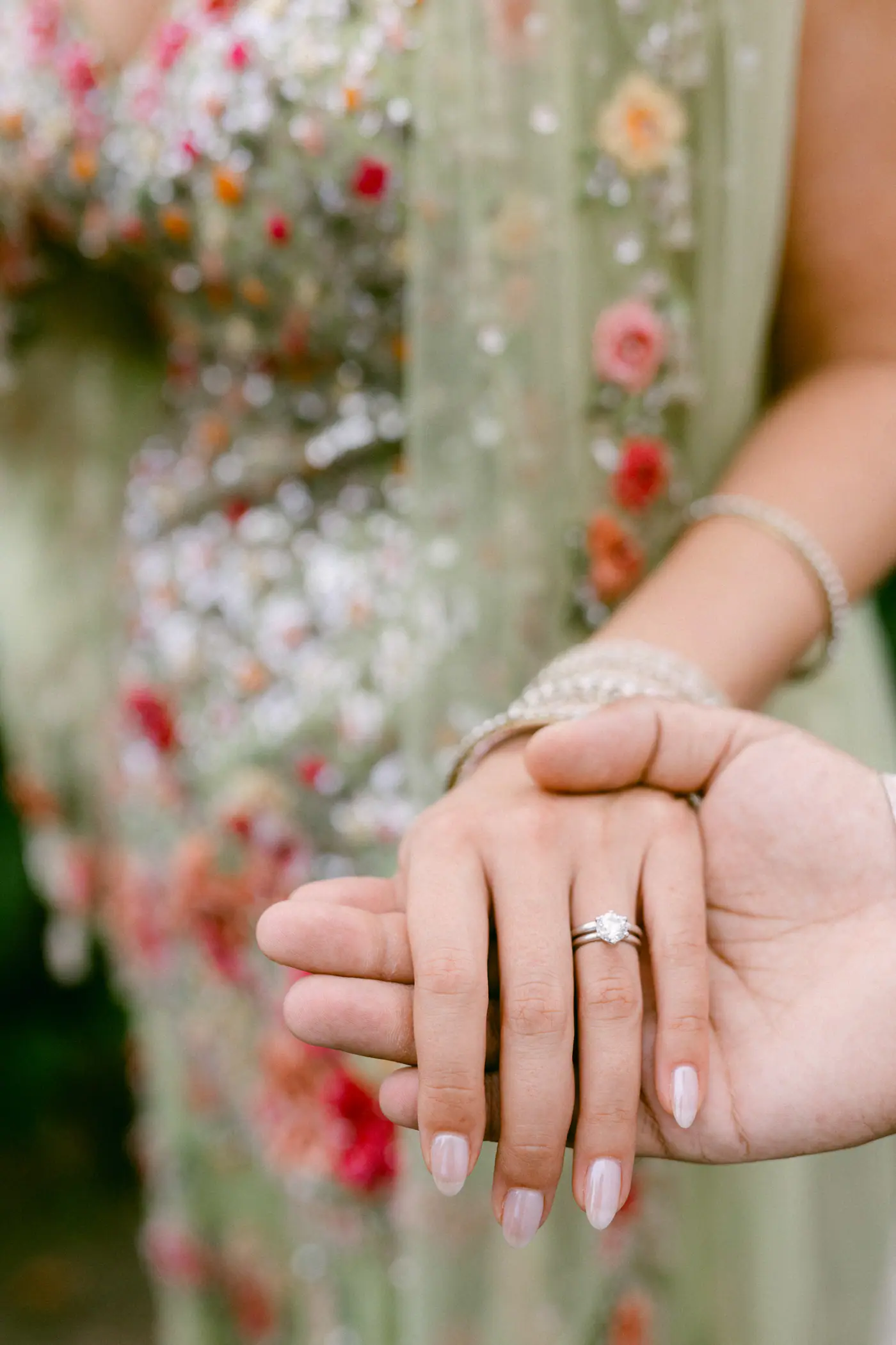 The bride’s hand with her engagement ring resting in the groom’s hand