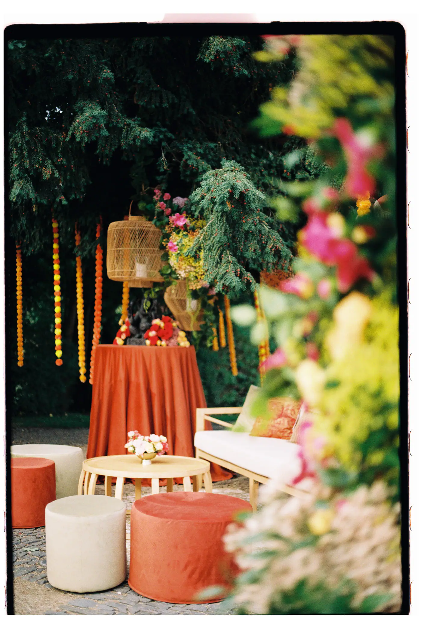 Garden lounge with orange and peach furniture among flowers and lanterns