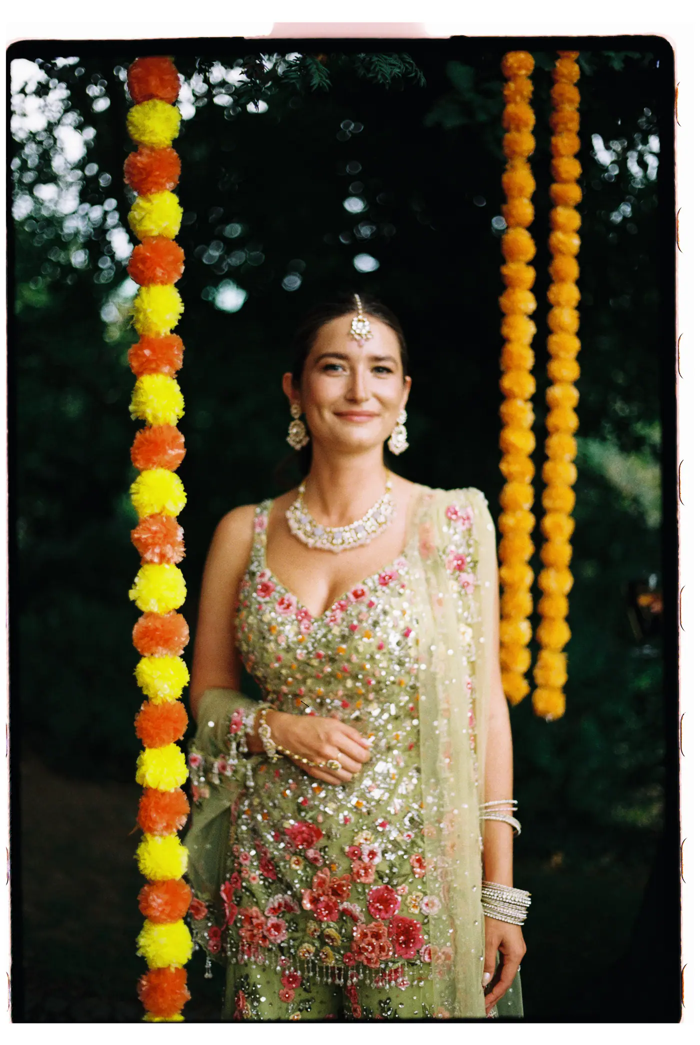 Bride smiling between hanging marigold garlands