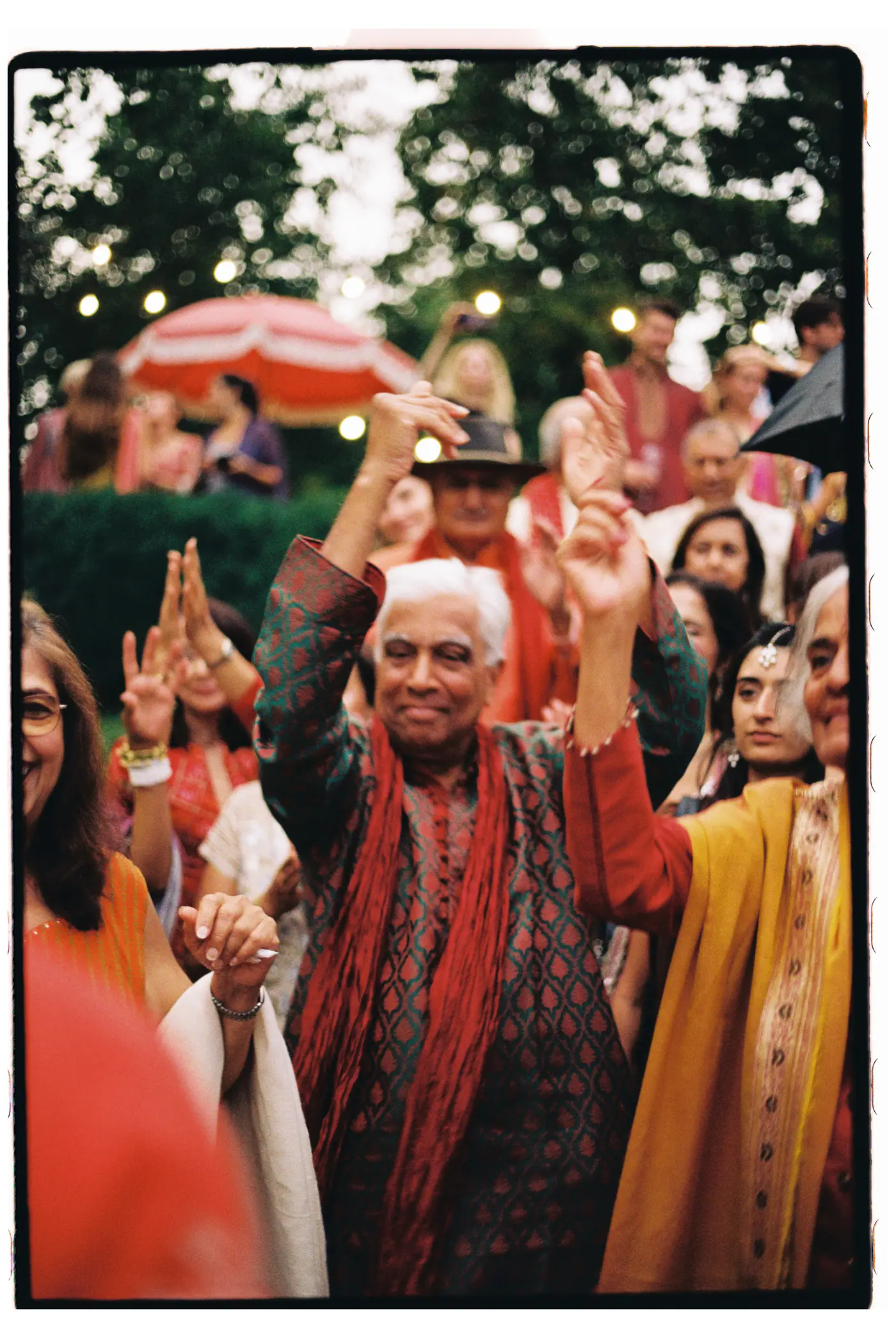 Older guest in a red shawl dancing with raised hands among the guests