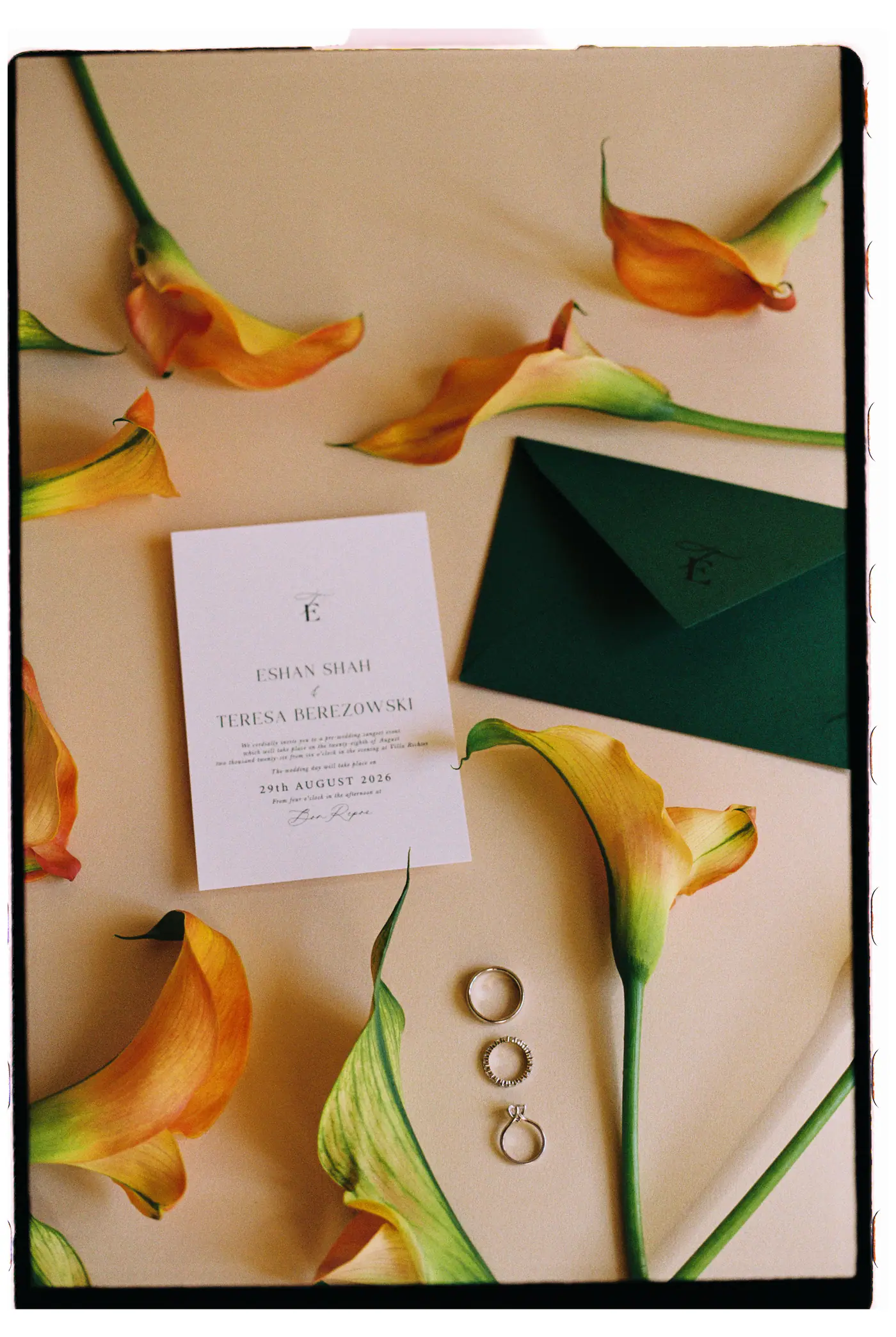 Wedding invitation, gold rings and orange calla lilies on a peach background