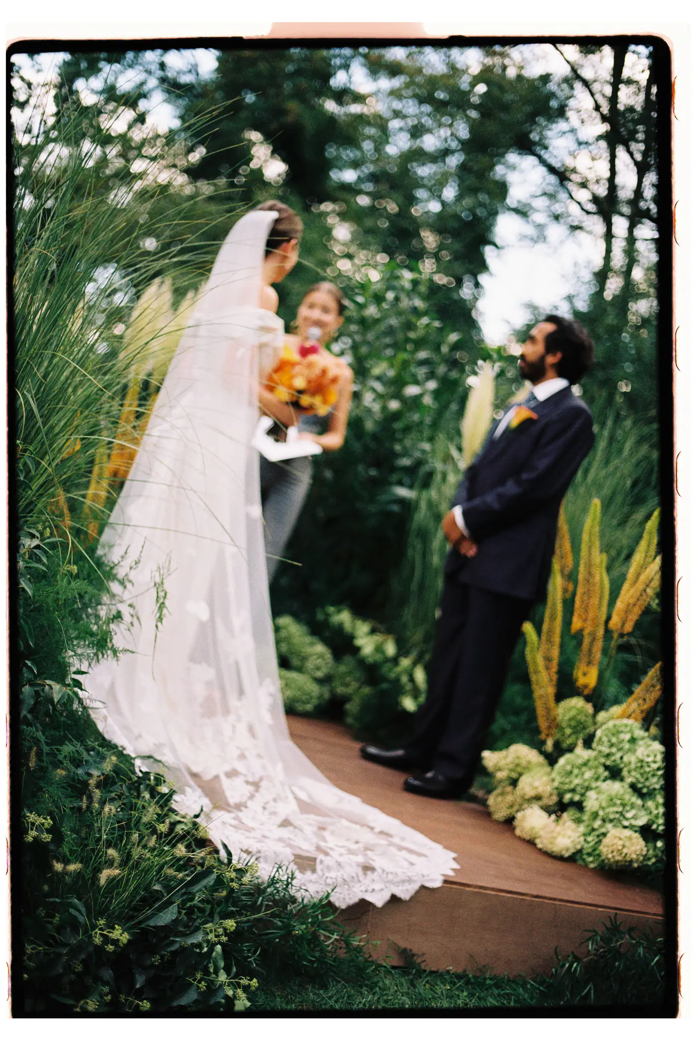 Bride and groom at the garden ceremony, her long lace train spread over the steps