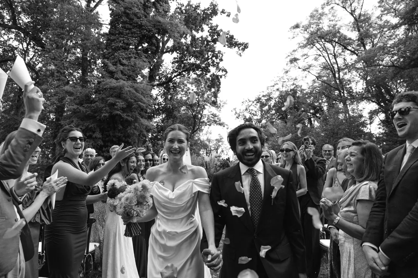 Black and white photo of the bride and groom walking through cheering guests after the ceremony