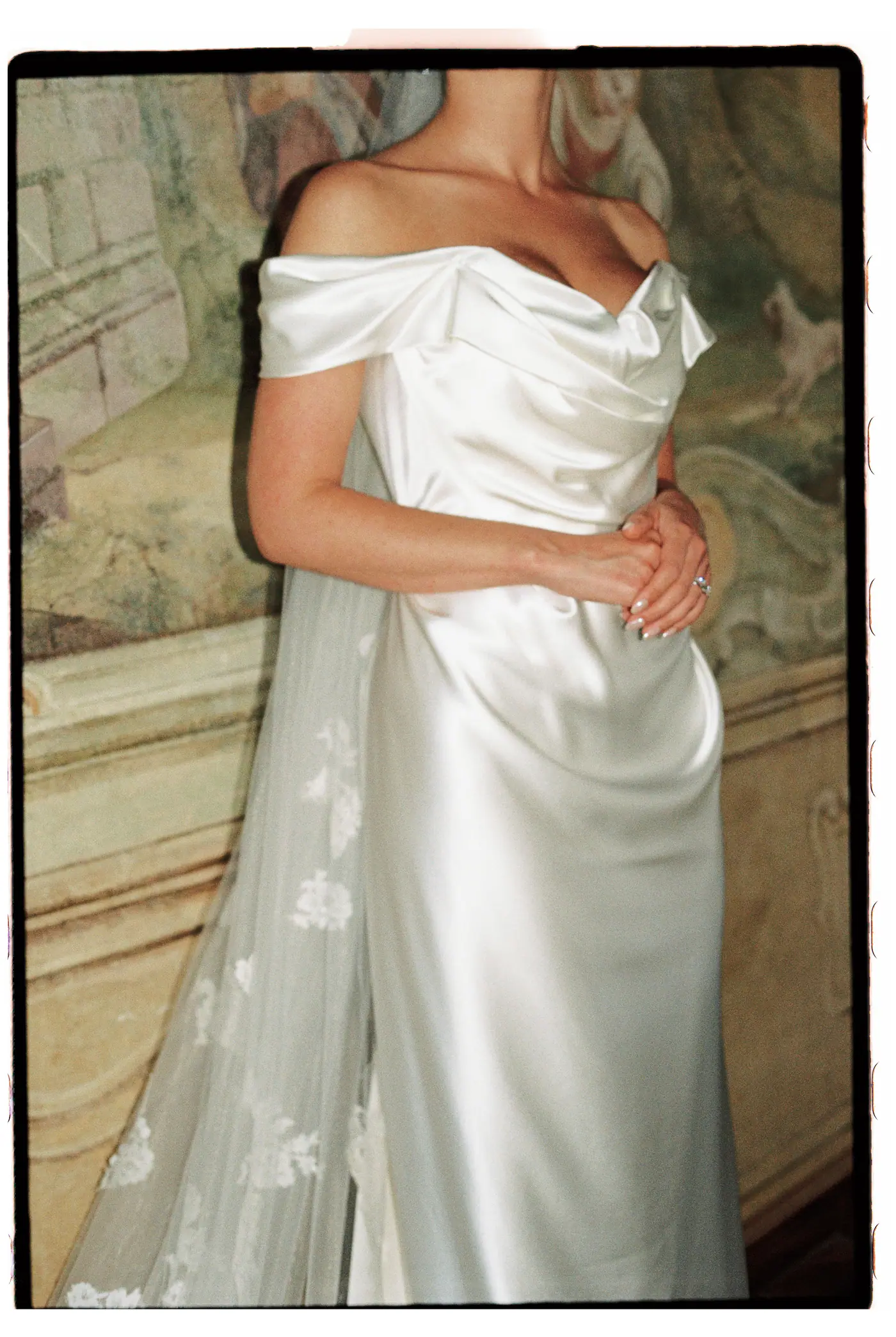 Bride in a satin dress and veil in front of a fresco
