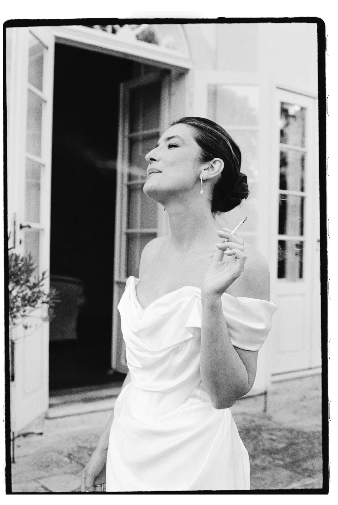 Black and white photo of the bride laughing in a doorway