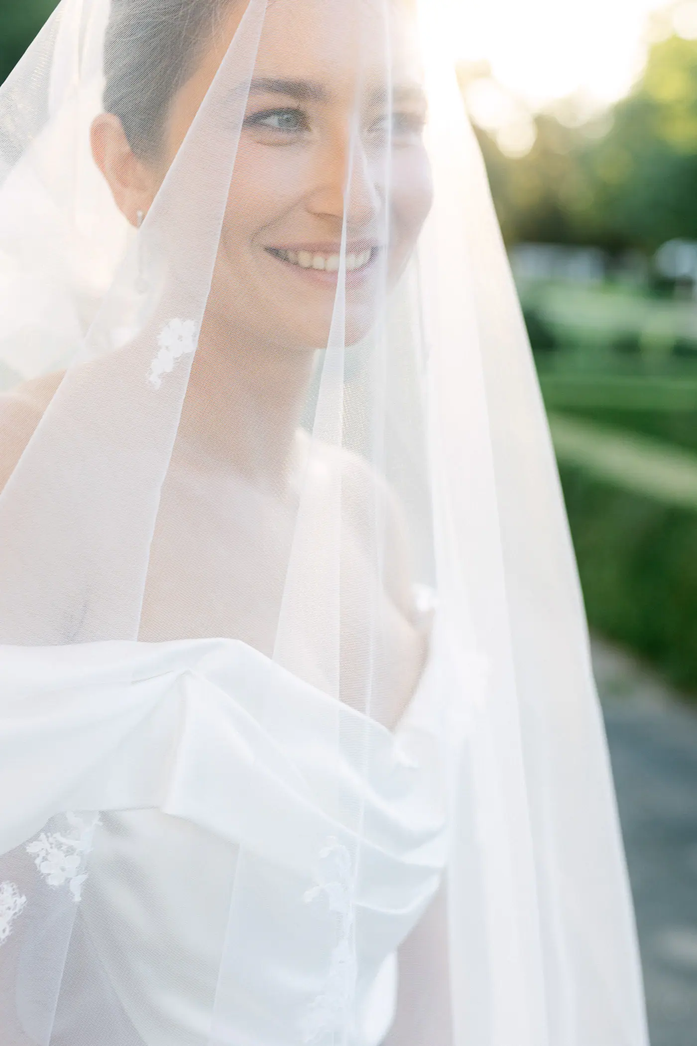 Bride smiling under her veil in the evening sun