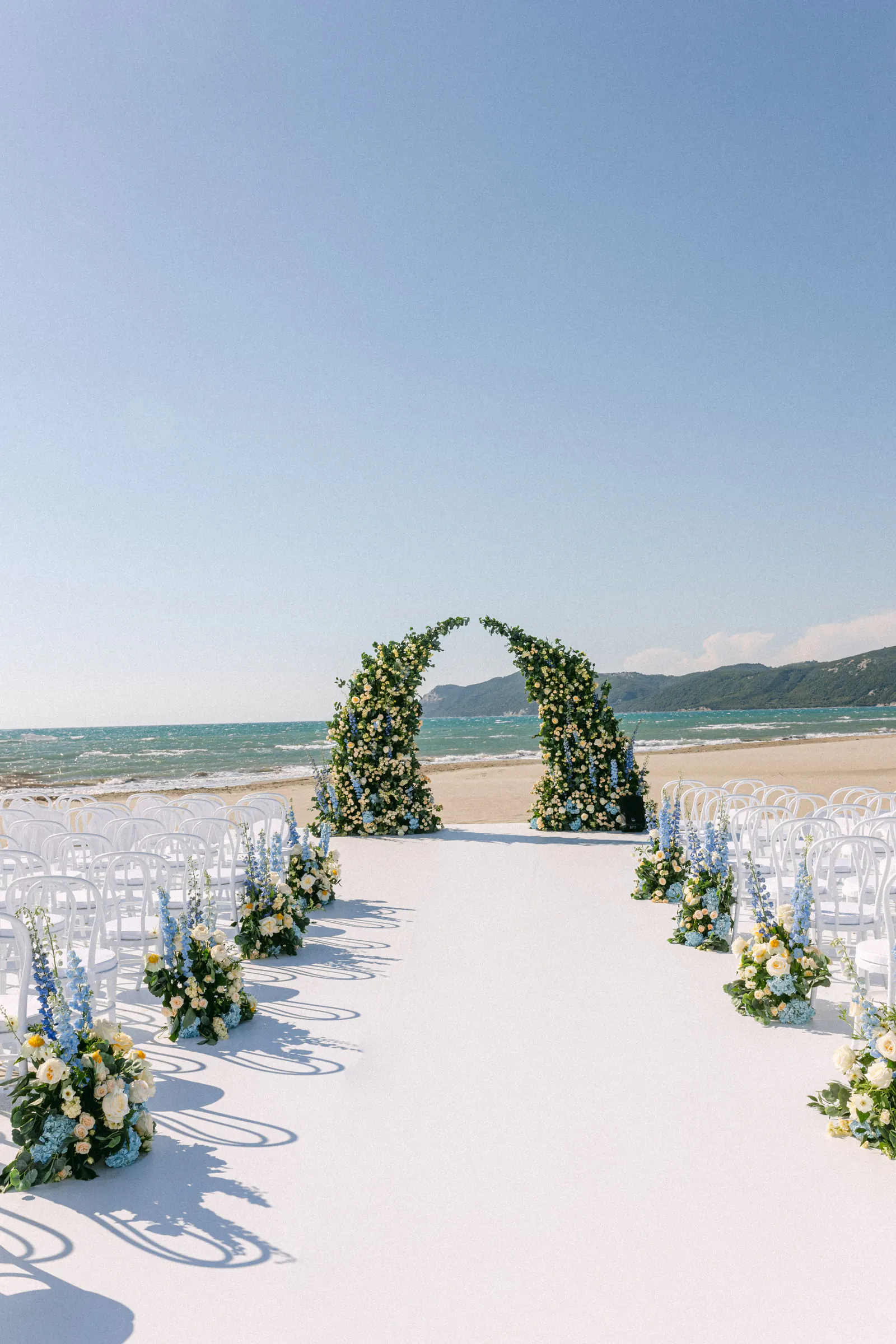 Wedding ceremony aisle with a floral arch on a sandy beach by the sea