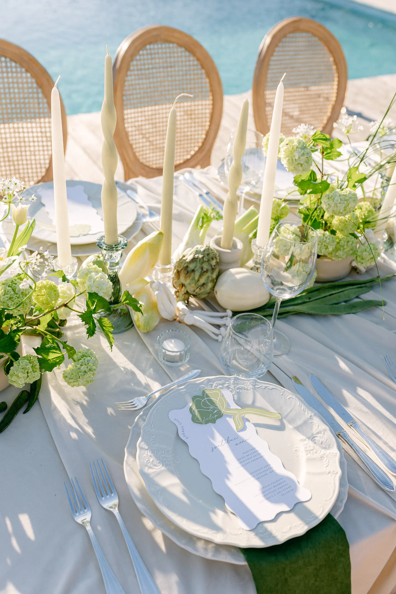 Wedding table with white rattan chairs and flowers beside a pool
