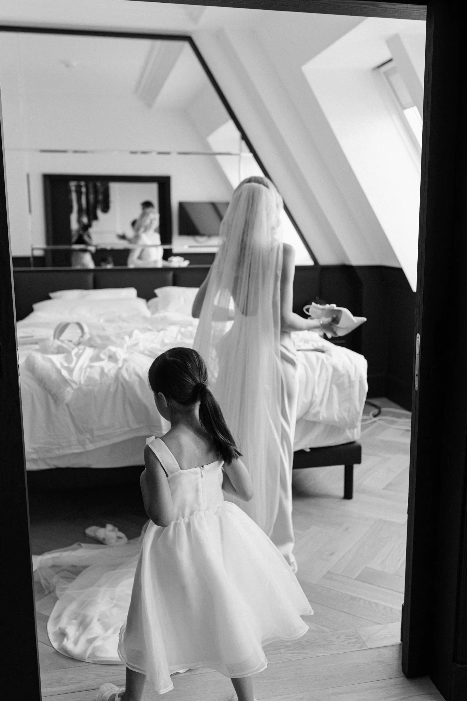 Black and white photo of a little girl watching the bride get ready