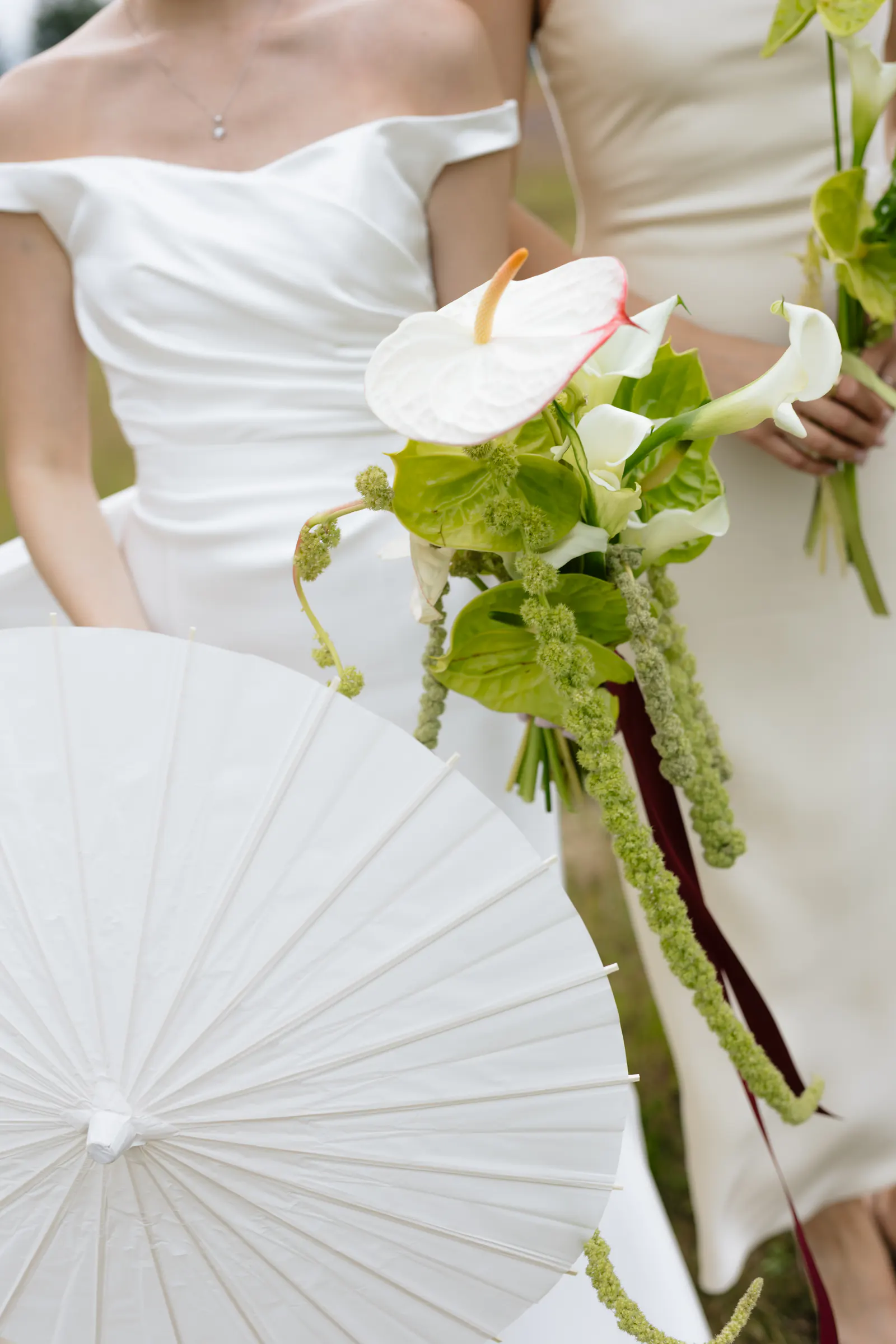 Bride holding calla lilies and a white paper parasol