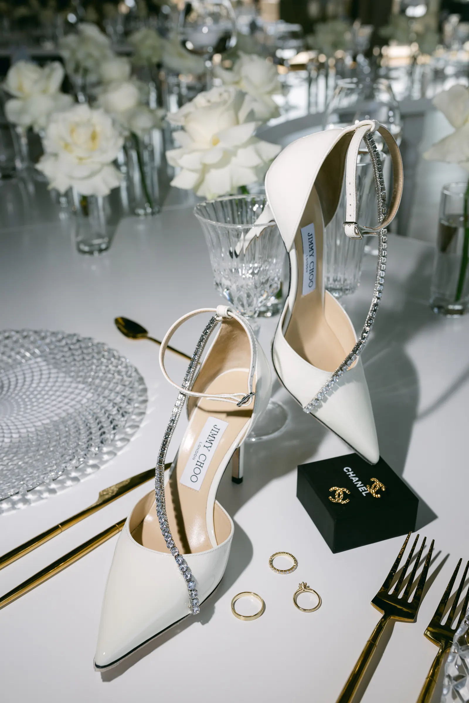 Bridal shoes, rings and glassware on a white wedding table