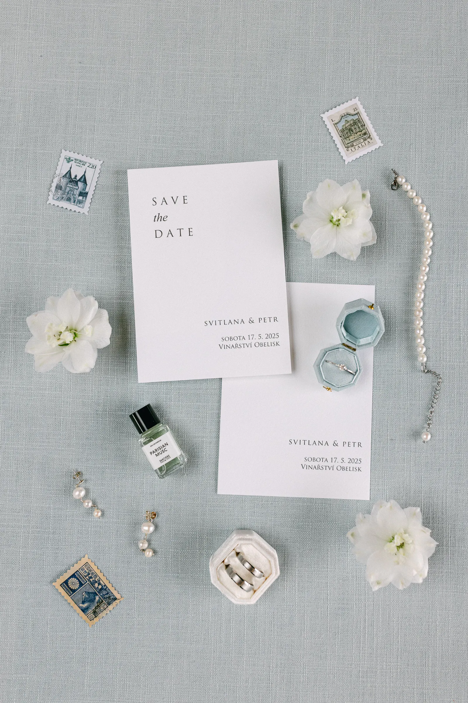 Save-the-date stationery with rings and white flowers on pale blue