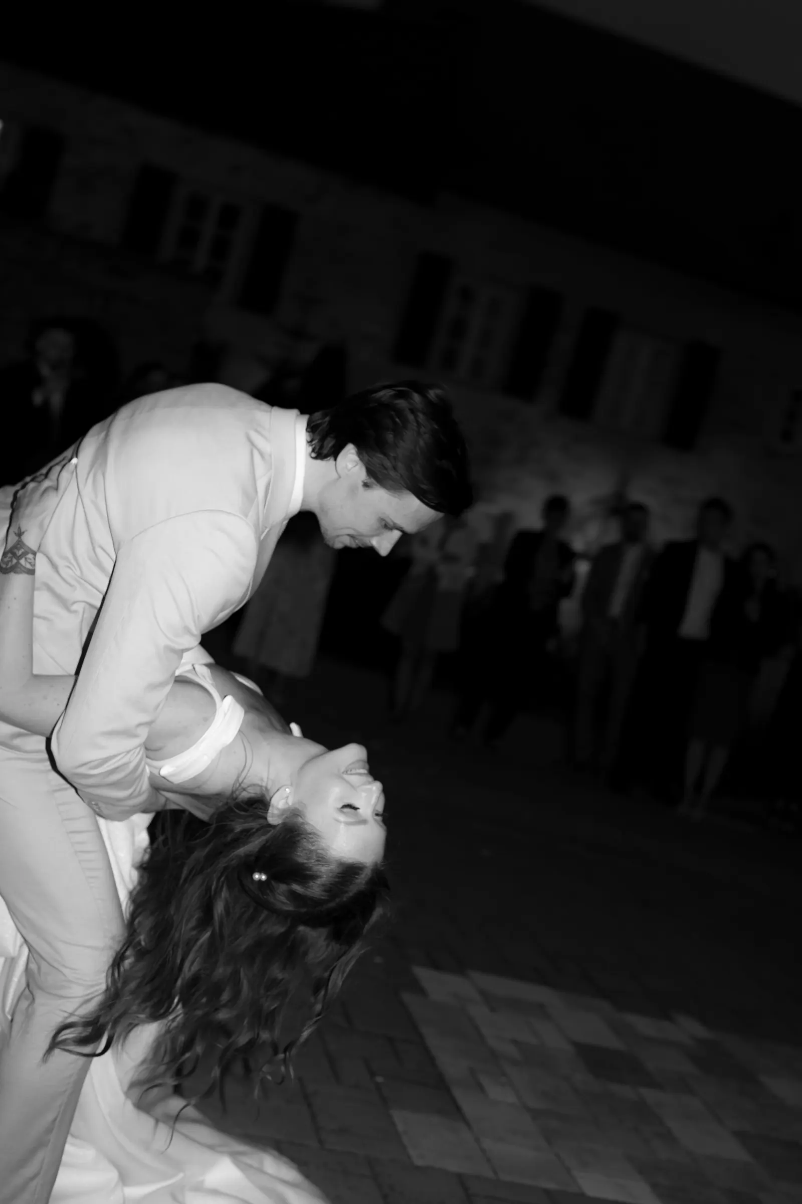 Black and white photo of the groom dipping the bride on the dance floor