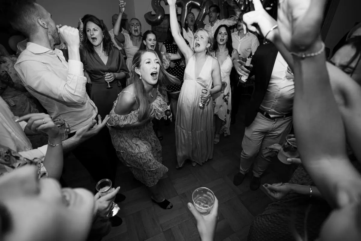 Black and white photo of guests dancing wildly at the wedding party